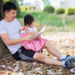 A Father is Reading A Book With Her Daughter