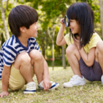 A young preschool boy and girl playing outdoors, symbolising the importance of social skills