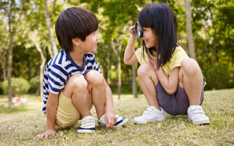 A young preschool boy and girl playing outdoors, symbolising the importance of social skills