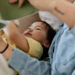 Reading literacy develops through various stages during early childhood, image shows a 0-2 year old reading in bed with a parent