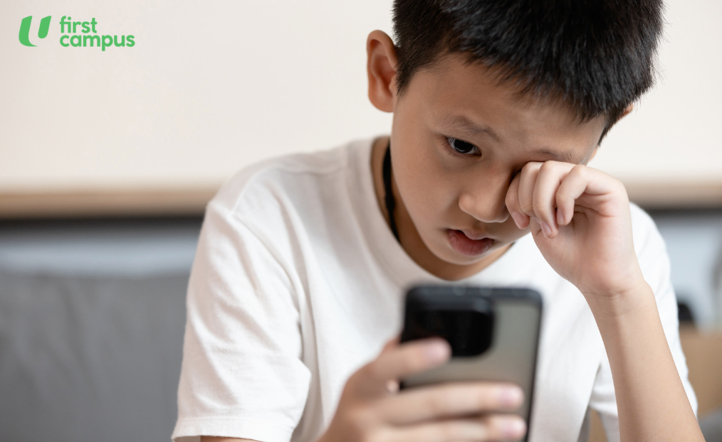 Boy rubbing his eyes while holding a mobile phone as excessive screen time can result in myopia