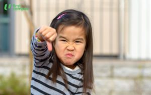 Preschool child throwing a temper tantrum with a frowning face and making a thumbs down sign